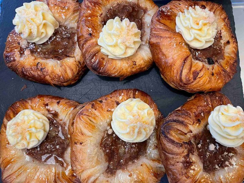Apple cinnamon pastries with a cream finish on a dark board