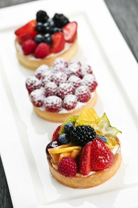 Three fruit tartlets arranged on a white platter