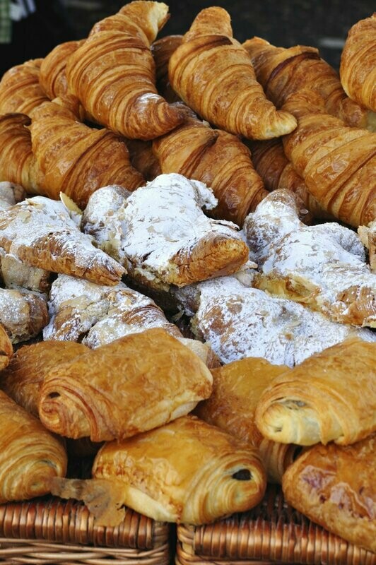Golden croissants and almond pastries piled in baskets