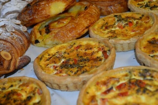 Individual quiches and pastries on a bakery tray